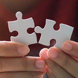 Close up shot hands of woman holding paper jigsaw puzzle image