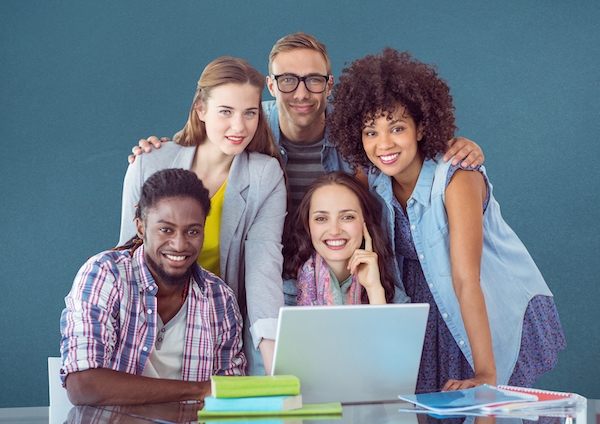 Portrait of happy classmates using laptop on table