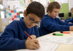 Child sitting at desk writing on test paper