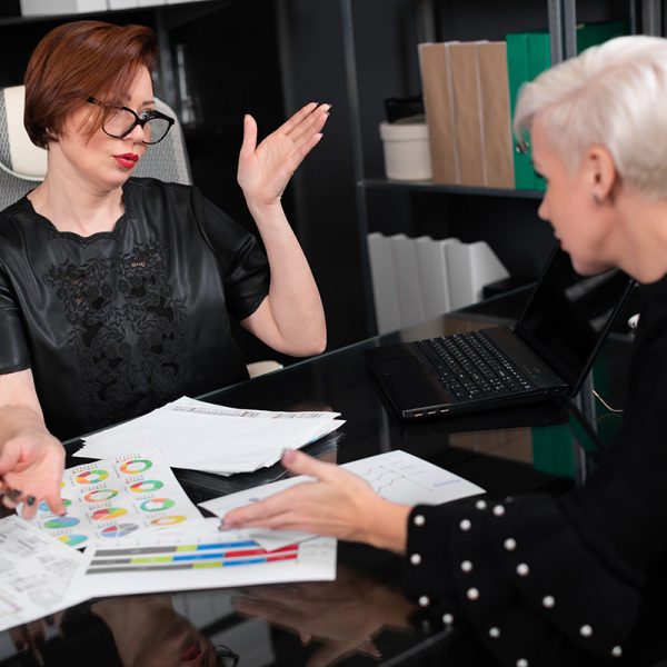 Business women discuss diagrams at Desk in office Group of successful businessmen. concept of reliable partnership. Business partners shake working with documents at office Desk. Two women discuss marketing plan