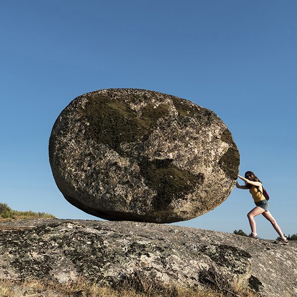 Woman pushing a world rock. Metaphor for the effort of working