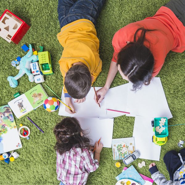 Children playing and drawing on green carpet