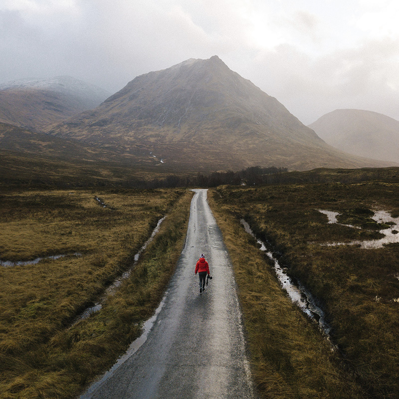 Woman walking on a road in Glen Etive, Scotland