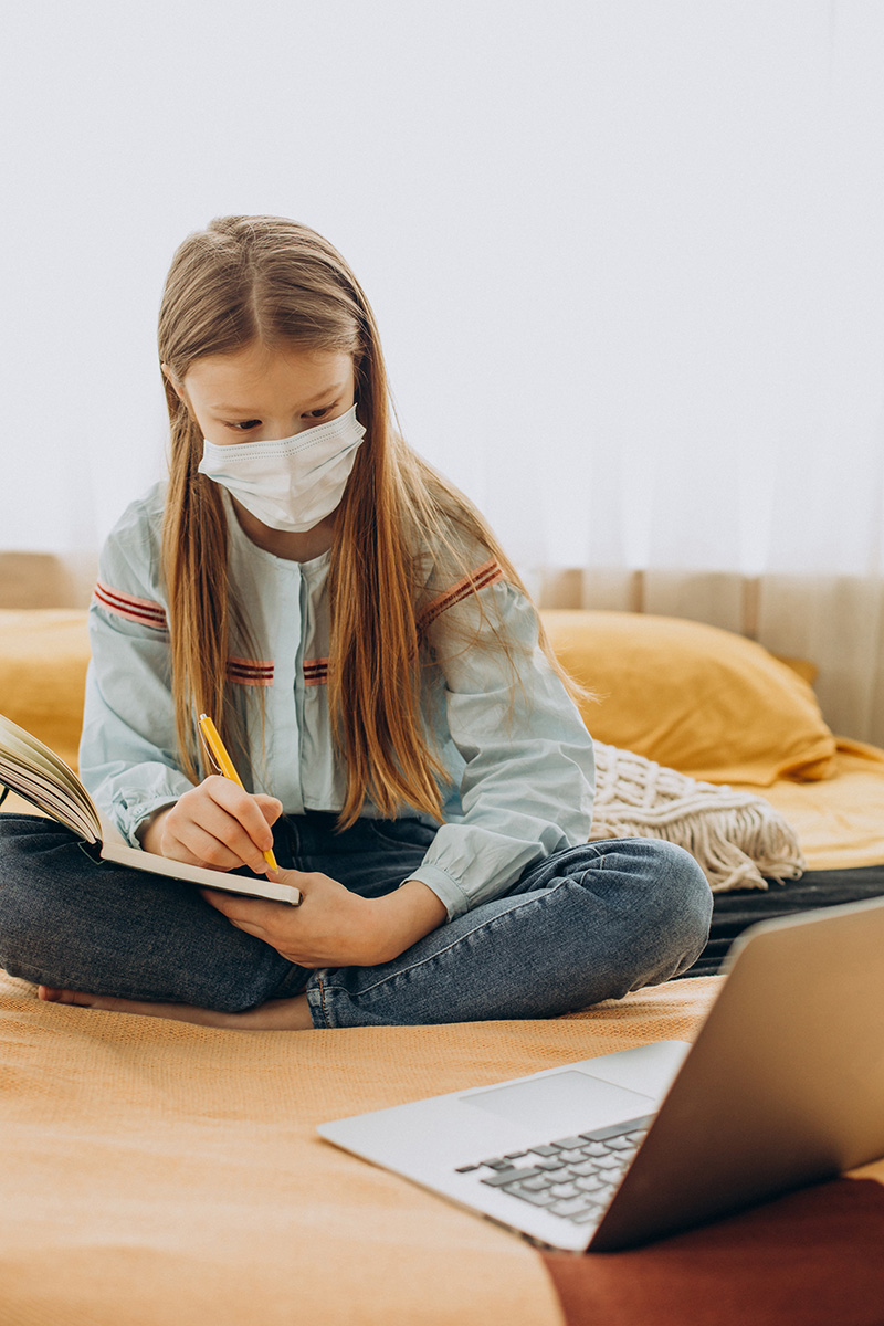 School girl studying at home wearing mask, distant learning