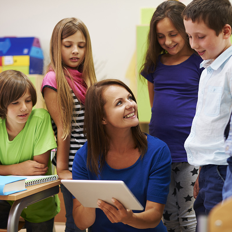 Woman holding pad with kids looking on