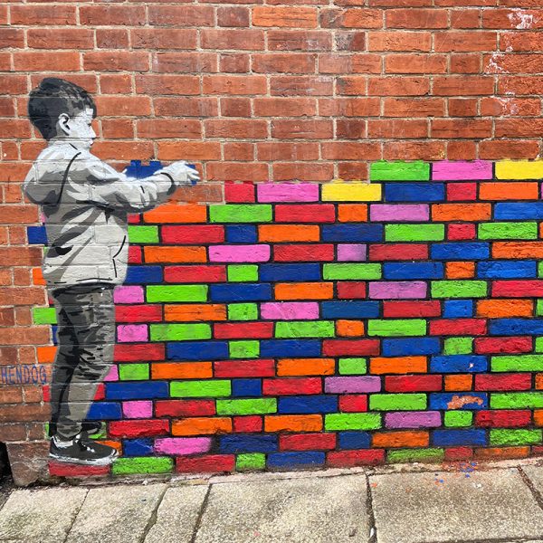 Child placing coloured bricks on a wall