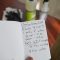 A selective focus shot of a hand holding cleaning concentrate handwritten recipe