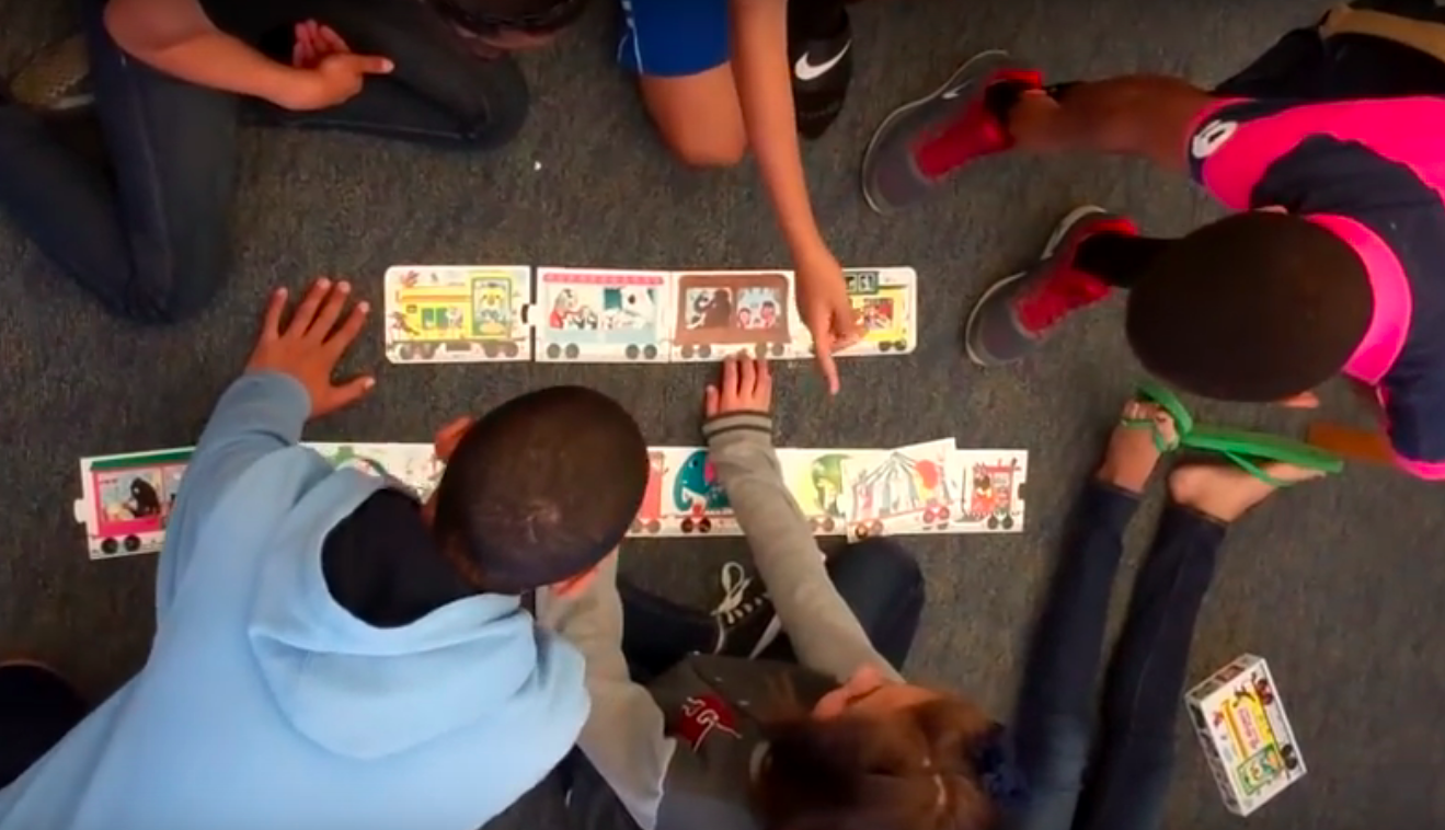 Kids playing with train cards on the ground