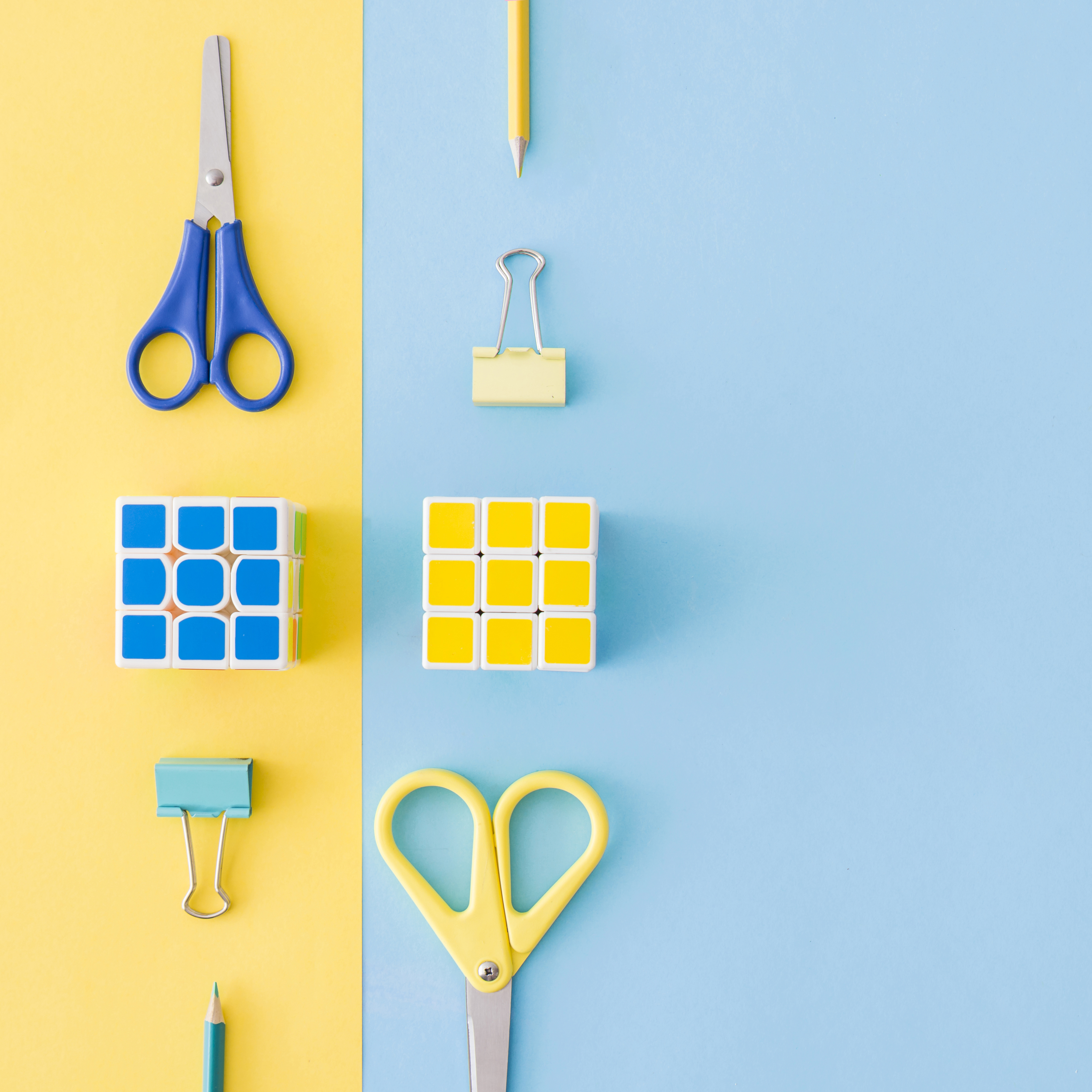 Rubik's and scissors on a colourful blue and yellow paper background