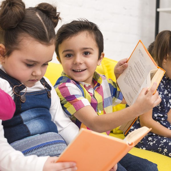 A group of children sitting on a lounge reading books