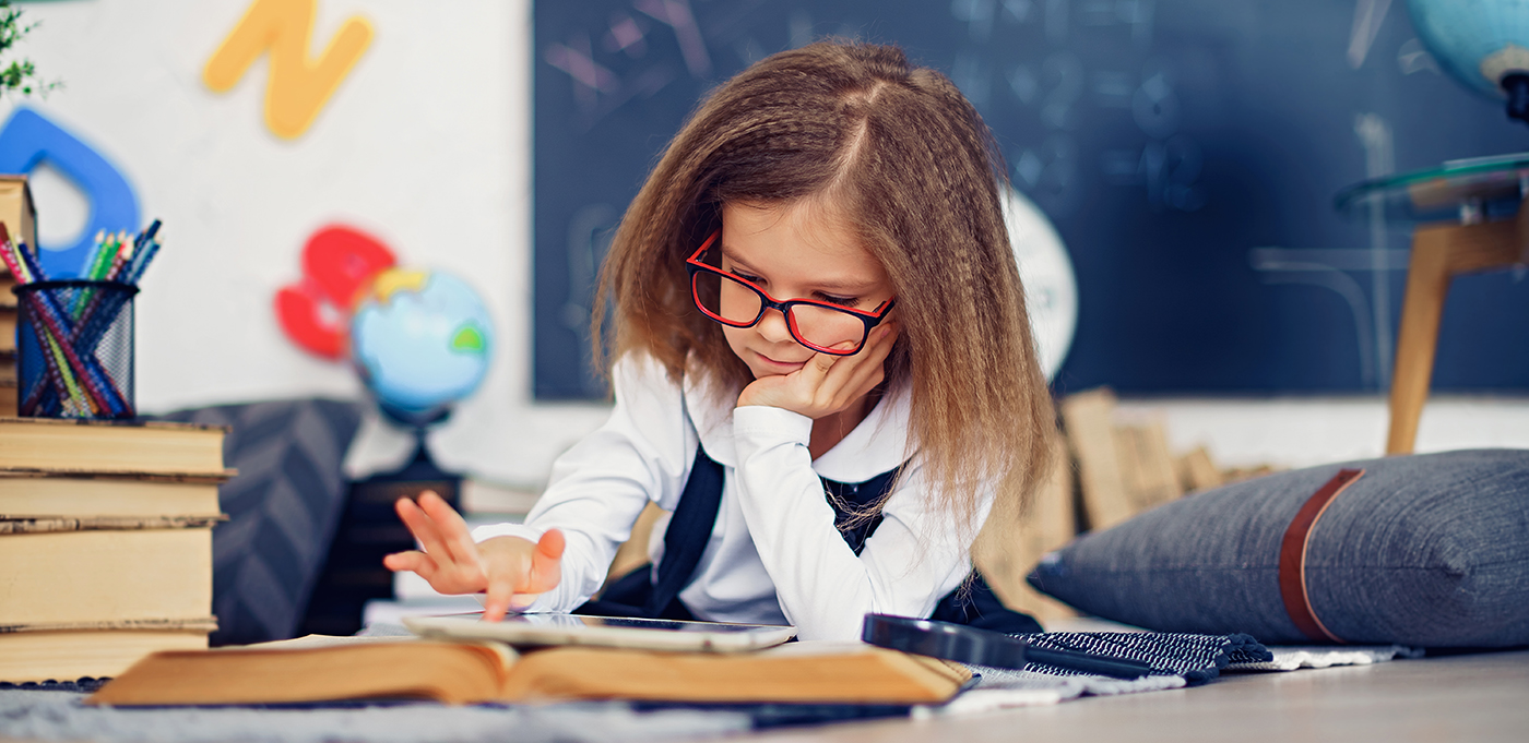 Young girl using a tablet on top of a book