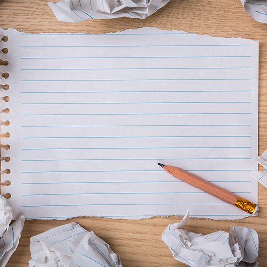 White note book paper with pencil and crumpled paper on a wood