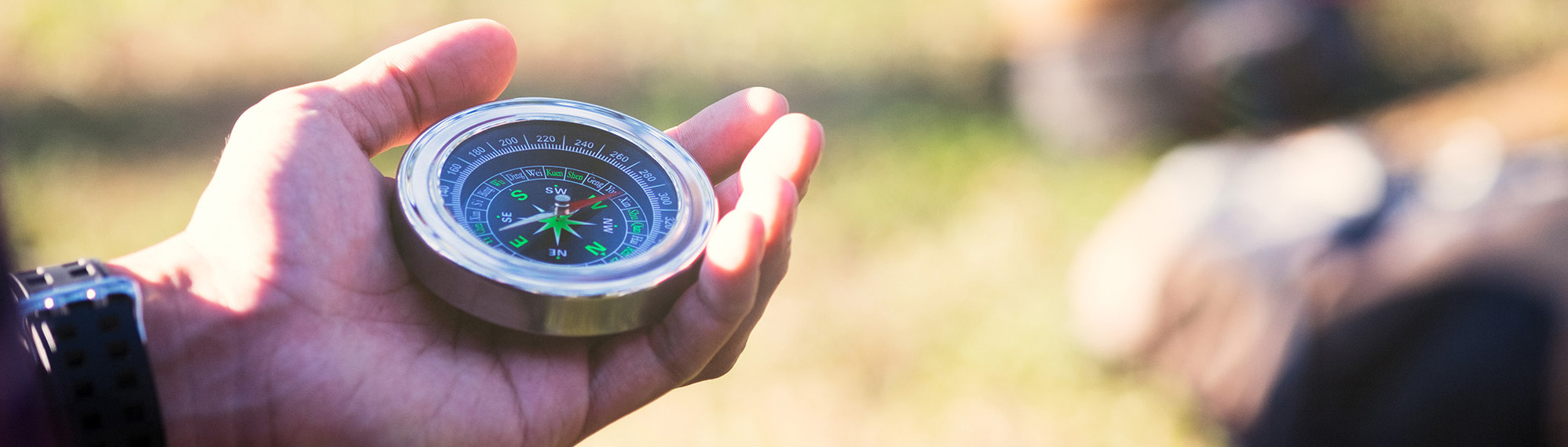 Hiker searching direction with a compass in the forest.