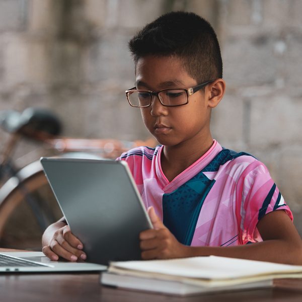 Boy reading on tablet whilst on laptop