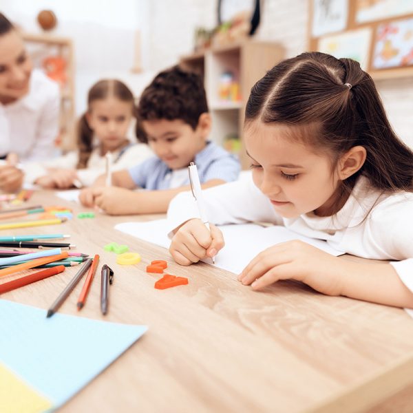 Children write in notebooks with a pen.