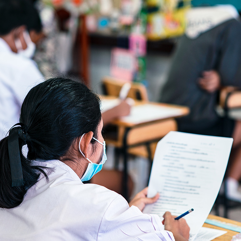 Students wearing mask for protect covid-19 and doing exam in classroom with stress