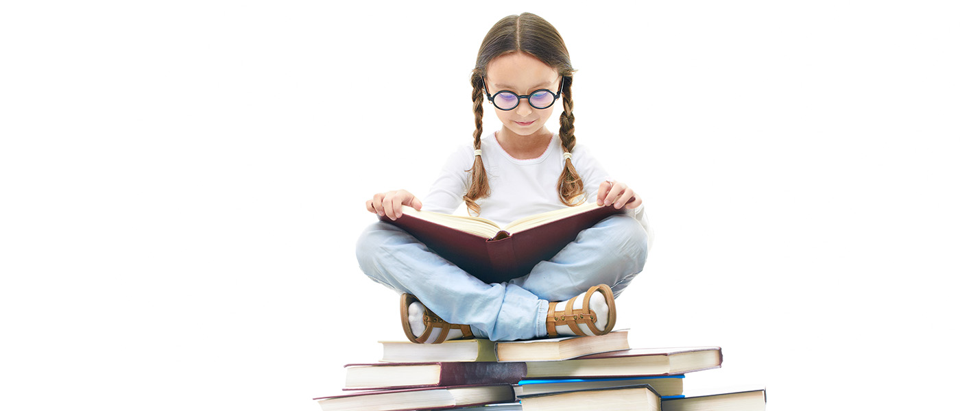 Portrait of girl with open book sitting on a pile of books