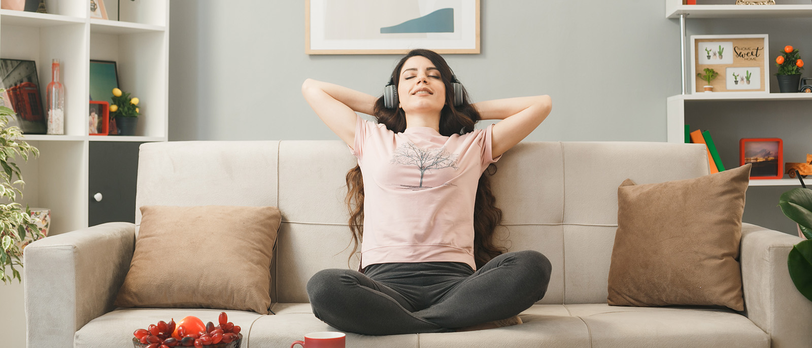 relaxed with closed eyes young girl wearing headphones sitting on sofa behind coffee table in living room