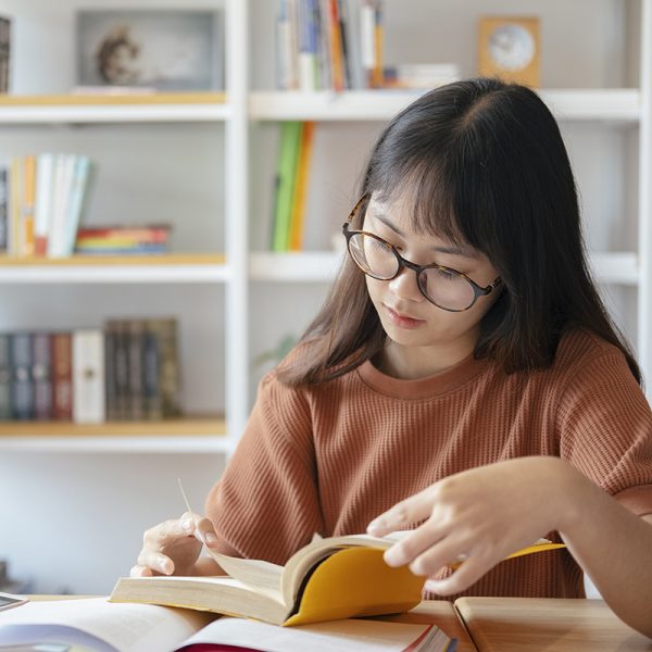 Collage female is reading a book.