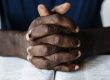 African American male hands resting on an open bible
