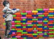 Child placing coloured bricks on a wall