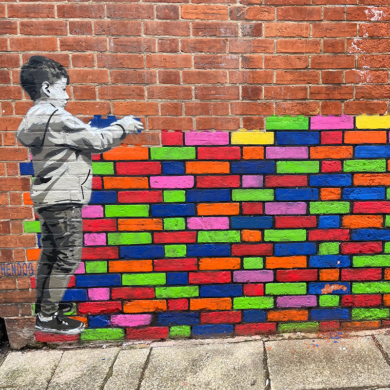 Child placing coloured bricks on a wall